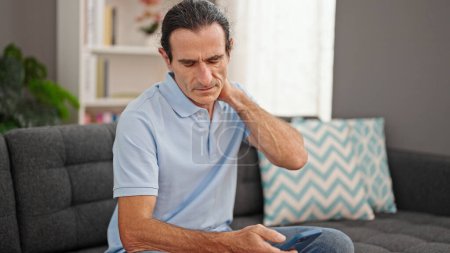 Photo for Middle age man using smartphone suffering for cervical pain at home - Royalty Free Image