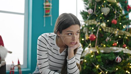 Photo for Young beautiful hispanic woman celebrating christmas sitting with serious expression at home - Royalty Free Image