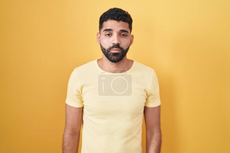 Téléchargez les photos : Homme hispanique avec barbe debout sur fond jaune l'air somnolent et fatigué, épuisé par la fatigue et la gueule de bois, les yeux paresseux le matin. - en image libre de droit