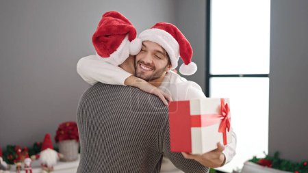 Foto de Dos hombres pareja celebrando navidad celebración regalo abrazándose entre sí en casa - Imagen libre de derechos