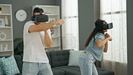 Téléchargez les photos : Homme et femme couple jouer jeu vidéo de boxe en utilisant des lunettes de réalité virtuelle à la maison - en image libre de droit