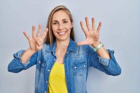 Téléchargez les photos : Jeune femme blonde debout sur fond bleu montrant et pointant vers le haut avec les doigts numéro neuf tout en souriant confiant et heureux. - en image libre de droit