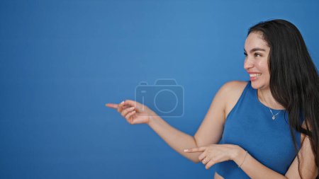 Photo for Young beautiful hispanic woman smiling pointing to the side with fingers over isolated blue background - Royalty Free Image