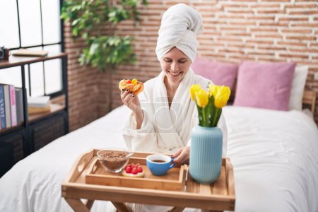 Photo for Young blonde woman wearing bathrobe having breakfast at bedroom - Royalty Free Image