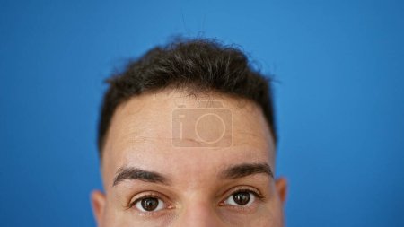 Téléchargez les photos : Jeune homme arabe gros plan des yeux sur fond bleu isolé - en image libre de droit