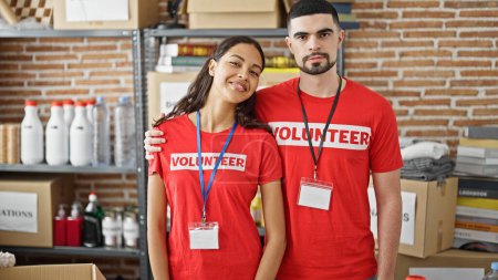 Téléchargez les photos : Des bénévoles souriants aiment se serrer dans leurs bras, se tenir debout dans un centre caritatif, s'unir dans un travail bénévole - en image libre de droit