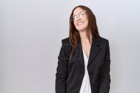 Photo for Beautiful brunette woman wearing business jacket and glasses looking away to side with smile on face, natural expression. laughing confident. - Royalty Free Image