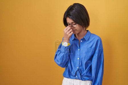 Photo for Young girl standing over yellow background tired rubbing nose and eyes feeling fatigue and headache. stress and frustration concept. - Royalty Free Image