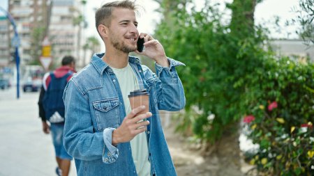 Téléchargez les photos : Jeune homme caucasien parlant sur smartphone boire du café au parc - en image libre de droit