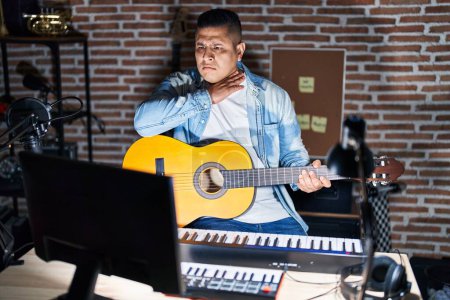 Téléchargez les photos : Jeune homme hispanique jouant de la guitare classique au studio de musique tranchant la gorge avec la main comme un couteau, menace d'agression avec une violence furieuse - en image libre de droit