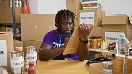 Téléchargez les photos : Afro-Américain volontaire souriant écriture confiante sur le document au centre de charité - en image libre de droit