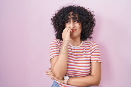 Photo for Young middle east woman standing over pink background looking stressed and nervous with hands on mouth biting nails. anxiety problem. - Royalty Free Image