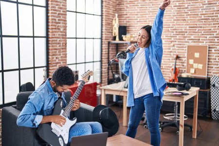 Foto de Man and woman musicians singing song playing electrical guitar at music studio - Imagen libre de derechos