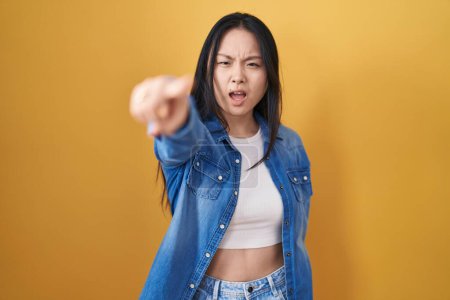 Téléchargez les photos : Jeune femme asiatique debout sur fond jaune pointant mécontent et frustré à la caméra, en colère et furieux contre vous - en image libre de droit