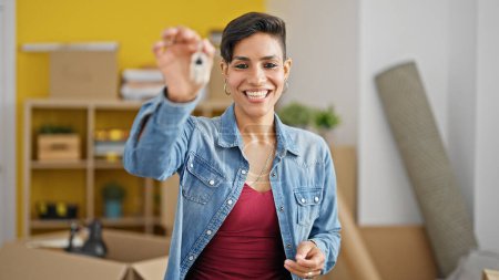 Photo for Young beautiful hispanic woman smiling confident holding key at new home - Royalty Free Image