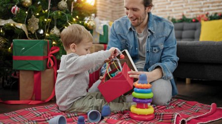 Foto de Padre e hijo desempacando regalo de Navidad jugando con juguetes en casa - Imagen libre de derechos