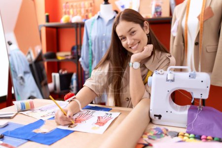 Téléchargez les photos : Jeune belle femme tailleur souriant conception de vêtements de dessin confiant à l'atelier - en image libre de droit