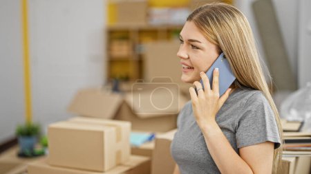 Photo for Young blonde woman talking on smartphone smiling at new home - Royalty Free Image