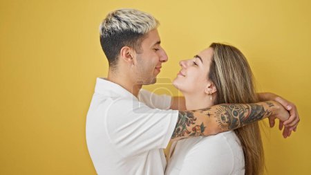 Téléchargez les photos : Beau couple souriant confiant étreignant et se regardant sur fond jaune isolé - en image libre de droit