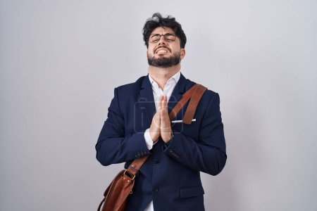 Photo for Hispanic man with beard wearing business clothes begging and praying with hands together with hope expression on face very emotional and worried. begging. - Royalty Free Image