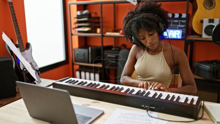 Foto de Músico afroamericano tocando piano usando laptop en estudio de música - Imagen libre de derechos