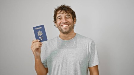 Photo for Smiling young man proudly holding his united states passport, radiating joy and confidence against isolated white background - Royalty Free Image