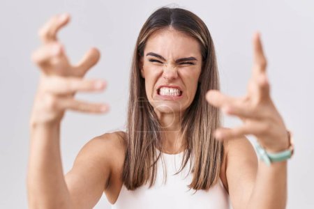 Téléchargez les photos : Jeune femme hispanique debout sur fond blanc criant frustré par la rage, les mains essayant d'étrangler, hurlant fou - en image libre de droit