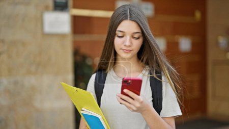 Photo for Young beautiful girl student using smartphone with serious face at school - Royalty Free Image