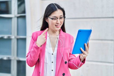 Foto de Mujer joven china usando touchpad usando auriculares sonriendo feliz señalando con la mano y el dedo - Imagen libre de derechos