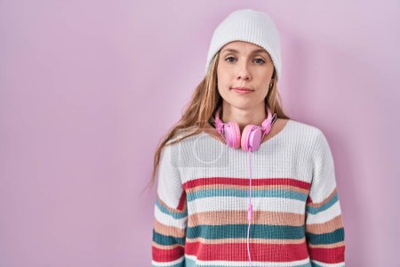 Foto de Young blonde woman standing over pink background relaxed with serious expression on face. simple and natural looking at the camera. - Imagen libre de derechos