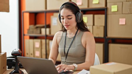 Téléchargez les photos : Jeune belle hispanique femme ecommerce travailleur d'affaires en utilisant un ordinateur portable et écouteurs au bureau - en image libre de droit