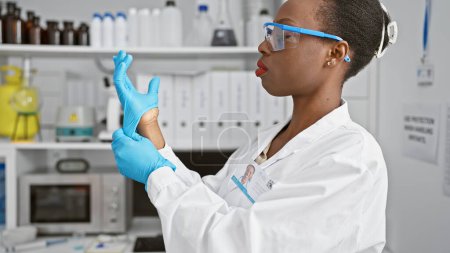 Foto de Científica afroamericana seria, vestida con guantes, trabajando diligentemente en la investigación médica en un laboratorio de alta tecnología, encarnando la hermosa esencia del profesionalismo - Imagen libre de derechos