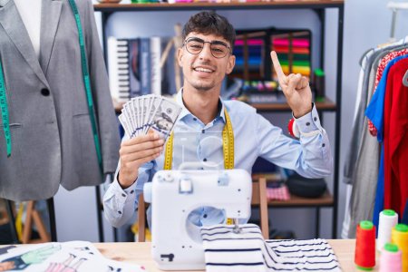 Photo for Young hispanic man dressmaker designer holding dollars smiling with an idea or question pointing finger with happy face, number one - Royalty Free Image