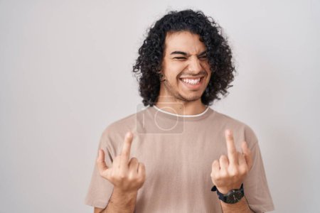 Photo for Hispanic man with curly hair standing over white background showing middle finger doing fuck you bad expression, provocation and rude attitude. screaming excited - Royalty Free Image
