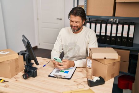 Foto de Hombre de mediana edad comercio electrónico trabajador de negocios utilizando el teléfono inteligente en la oficina - Imagen libre de derechos