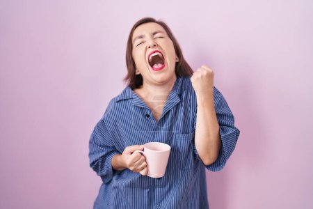 Photo for Middle age hispanic woman drinking a cup coffee very happy and excited doing winner gesture with arms raised, smiling and screaming for success. celebration concept. - Royalty Free Image