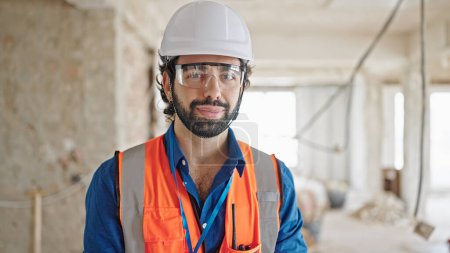 Photo for Young hispanic man architect standing with serious face at construction site - Royalty Free Image