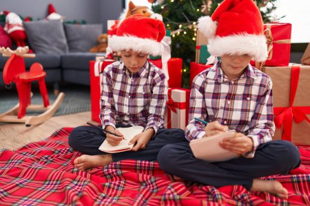 Photo for Adorable boys drawing on notebook celebrating christmas at home - Royalty Free Image