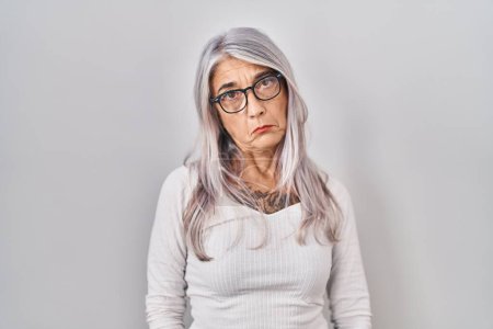 Foto de Mujer de mediana edad con el pelo gris de pie sobre fondo blanco deprimido y la preocupación por la angustia, llorando enojado y miedo. expresión triste. - Imagen libre de derechos