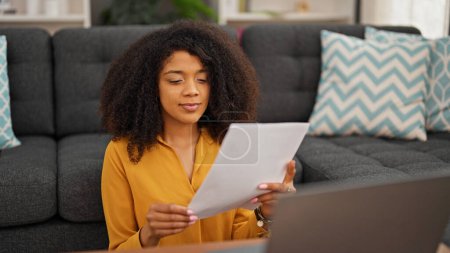 Foto de Mujer afroamericana usando el documento de lectura portátil en casa - Imagen libre de derechos