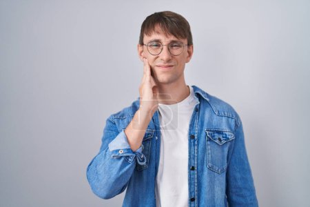 Photo for Caucasian blond man standing wearing glasses touching mouth with hand with painful expression because of toothache or dental illness on teeth. dentist - Royalty Free Image