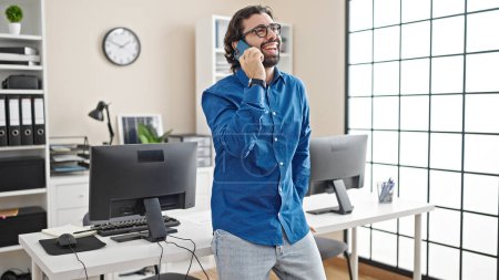 Photo for Young hispanic man business worker talking on smartphone working at the office - Royalty Free Image