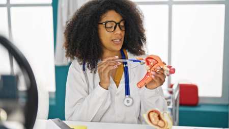 Photo for African american woman gynecologist doctor recording video tutorial of uterus at clinic - Royalty Free Image