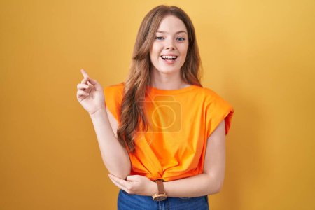 Photo for Caucasian woman standing over yellow background with a big smile on face, pointing with hand finger to the side looking at the camera. - Royalty Free Image
