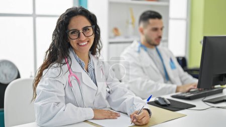Téléchargez les photos : Médecins hommes et femmes utilisant l'ordinateur prenant des notes souriantes à la clinique - en image libre de droit