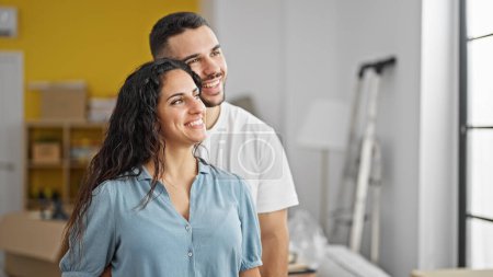 Photo for Man and woman couple standing together looking throw the window at new home - Royalty Free Image