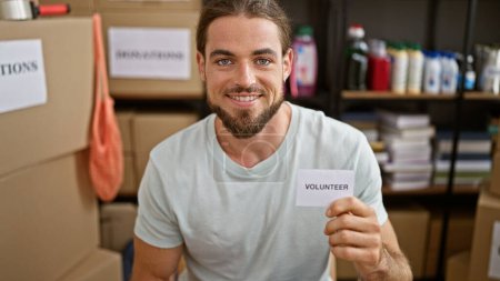 Téléchargez les photos : Jeune homme hispanique tenant du papier bénévole souriant au centre caritatif - en image libre de droit