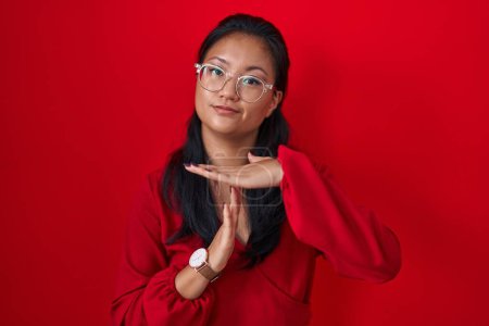 Photo for Asian young woman standing over red background doing time out gesture with hands, frustrated and serious face - Royalty Free Image