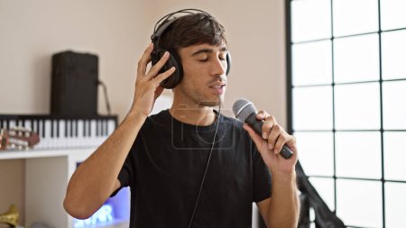 Foto de El joven hispano se inclina hacia la melodía, cantando su corazón en el estudio de música, perdido en el sonido de su propia voz - Imagen libre de derechos
