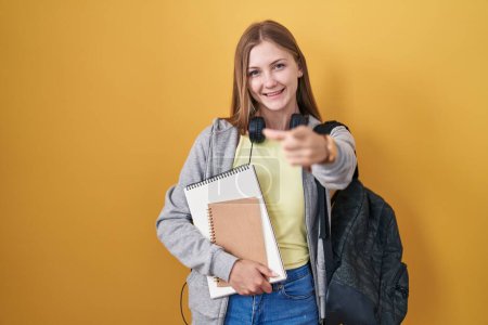 Photo for Young caucasian woman wearing student backpack and holding books pointing fingers to camera with happy and funny face. good energy and vibes. - Royalty Free Image